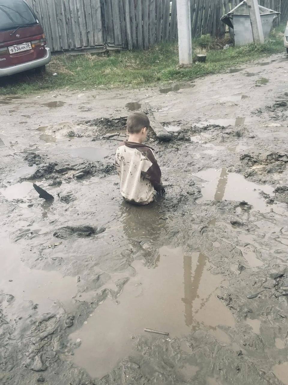 Спасатели вытаскивают мальчика из грязевой ямы на дороге