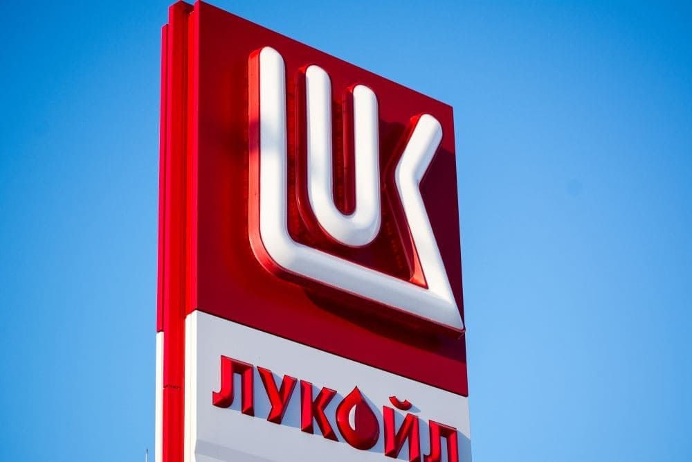 Флаг США и логотип Лукойла на фоне нефтяных вышек