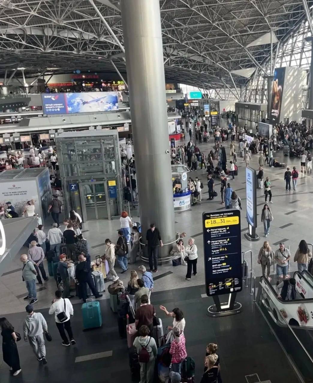Толпа пассажиров у табло в аэропорту с задержками