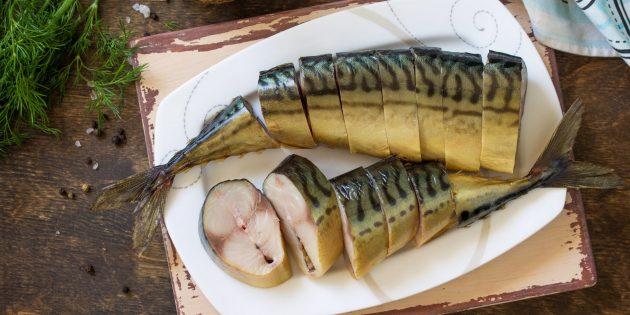 Свежая скумбрия на льду с зеленью и лимоном